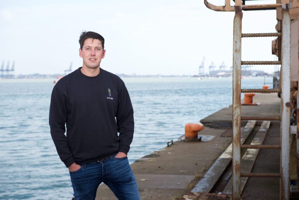 Luke Strudley stands looking out to the North Sea, with oil rigs in the background