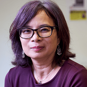 A woman with purple hair, purple top and glasses. She represents someone who has turned to the SCQF for help
