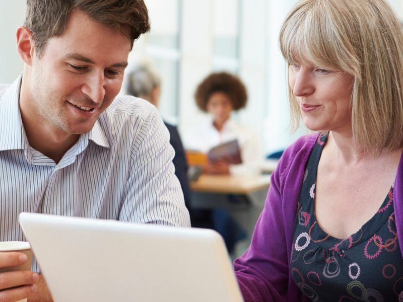 A man and woman are looking at a laptop screen. They represent employers whom the SCQF supports through its Inclusive Recruiter scheme