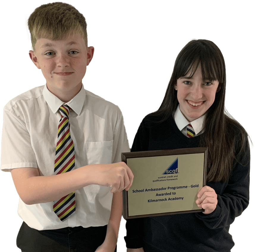 Two smiling school pupils from Kilmarnock Academy hold up a gold SCQF School Ambassador plaque. The school features on the SCQF School Ambassador Wall