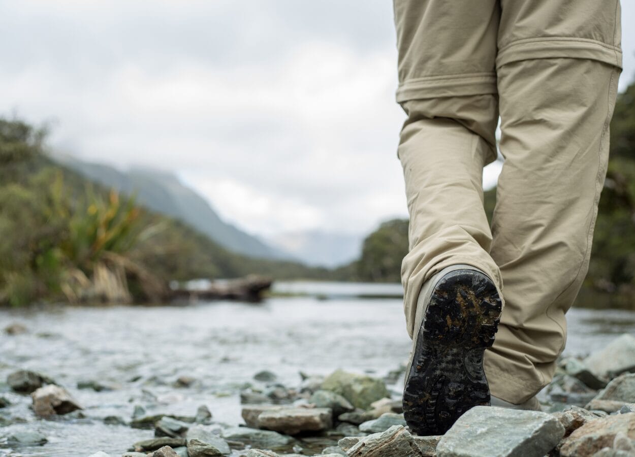 A person in khaki trousers walking along a bumpy, stone-filled, path in Scotland. It signifies the journey that learners take and their path through the SCQF levels