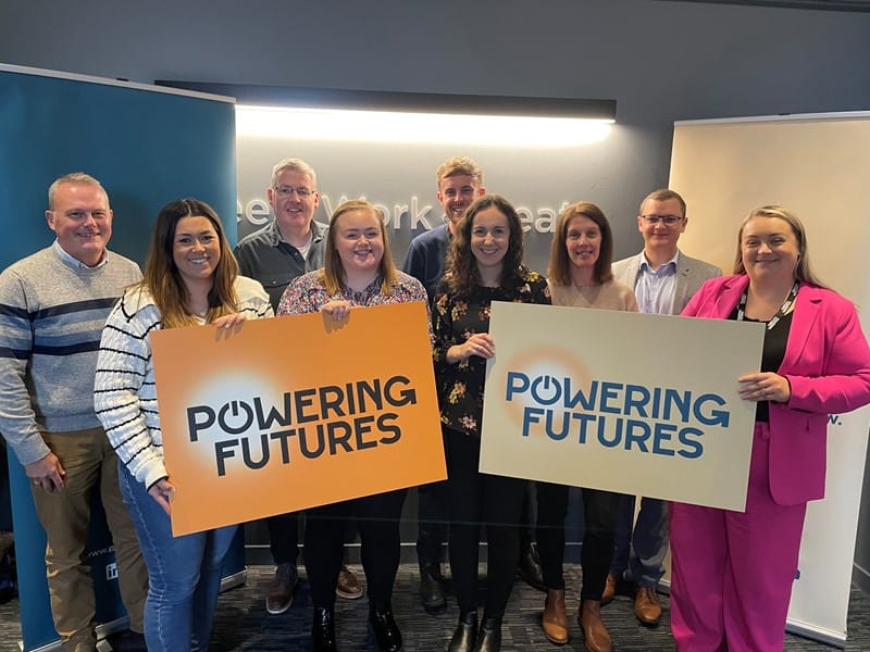 Group shot of the Powering Futures team holding up large signs featuring the Powering Futures logo