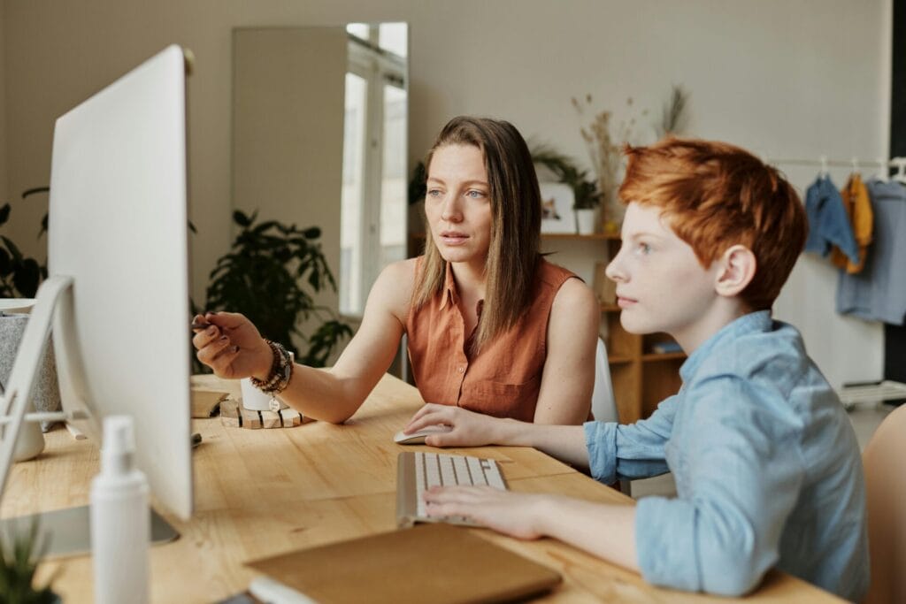 A parent and her son doing homework together on a laptop