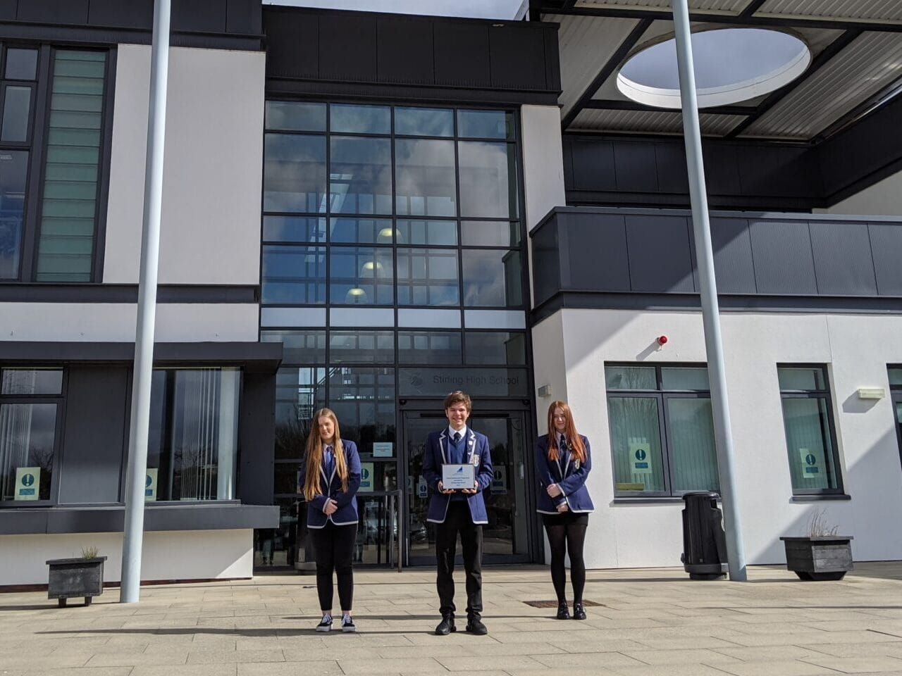 Stirling High School SCQF Ambassadors stand outside their school with the silver SCQF plaque
