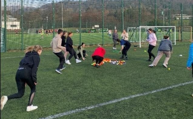 Young people on a green pitch, playing a game. Some of them are running. The activity is being run by Actify