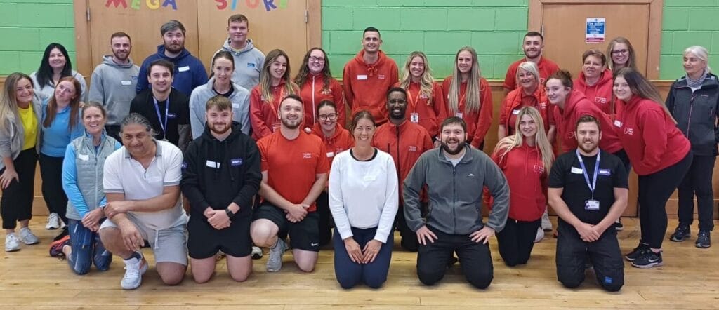 A group of Actify participants in a sports hall, smiling for the camera
